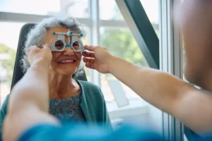 Blog 14 senior eye exam frequency The Villages – older woman smiling during vision test with optometrist